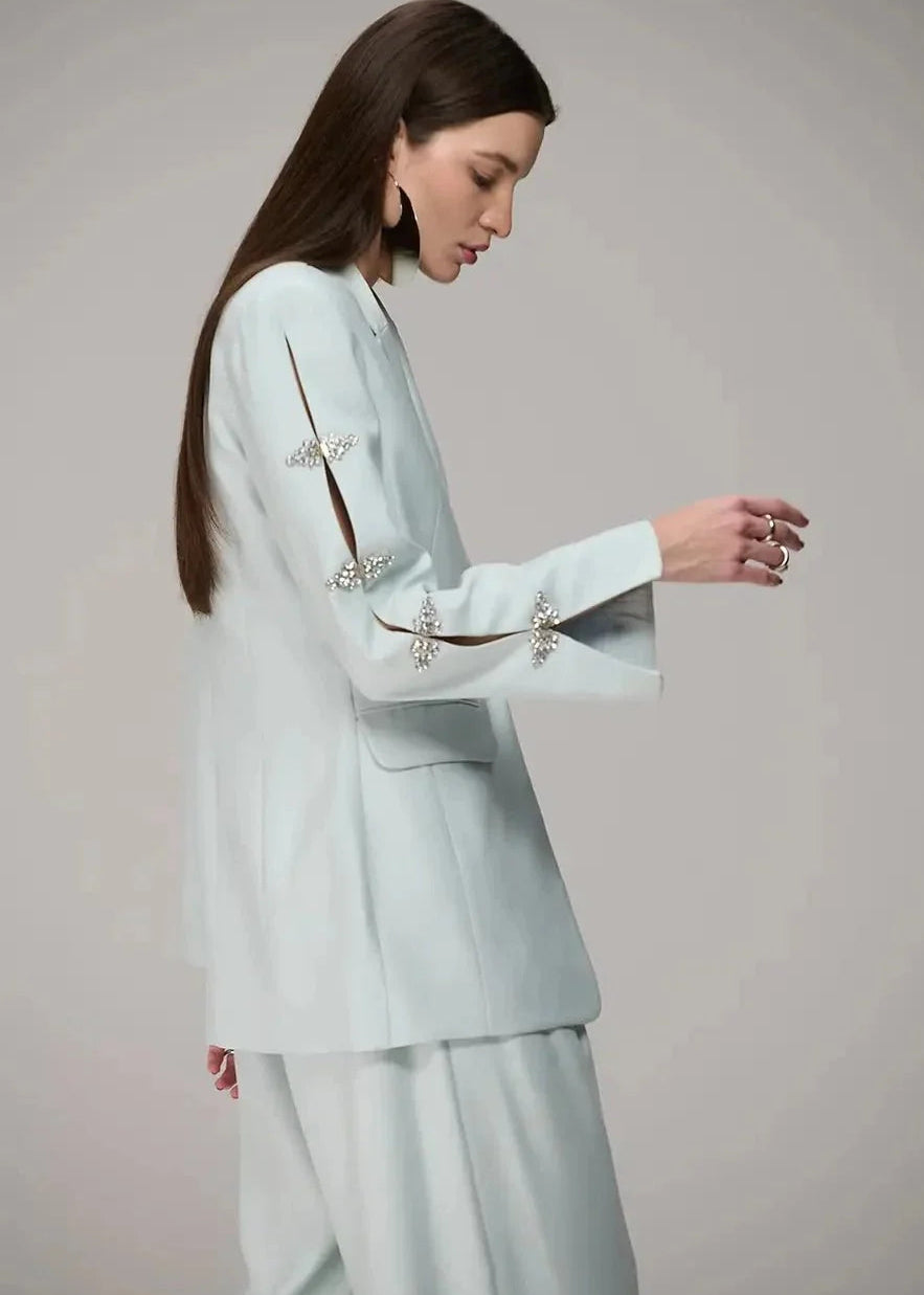 Woman wearing a light blue suit with decorative elements on a plain background
