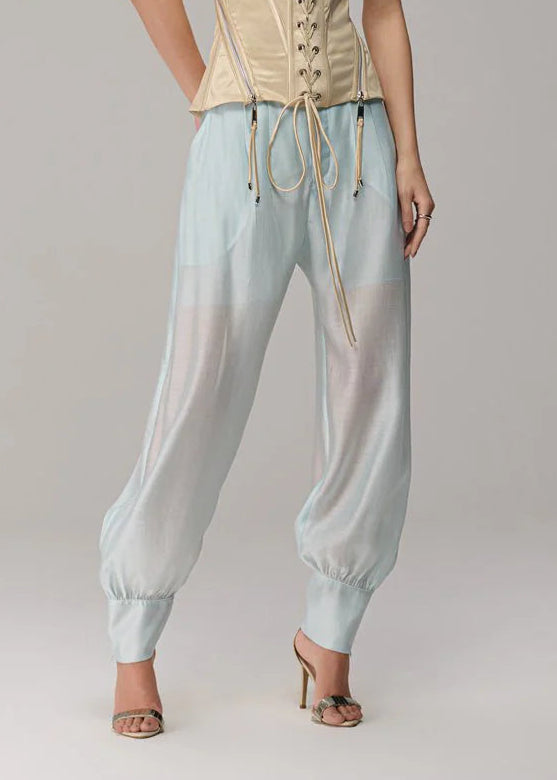 Woman wearing a beige strapless top and light blue pants on a gray background