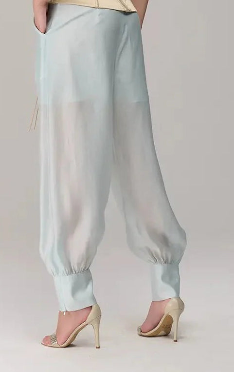 Woman wearing a strapless top and light blue pants on a plain background