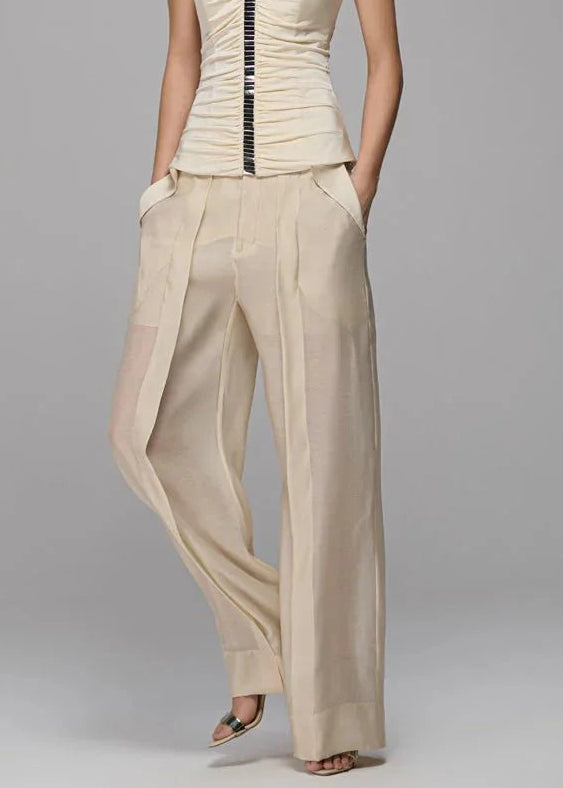Woman wearing a strapless top and wide-leg pants on a gray background