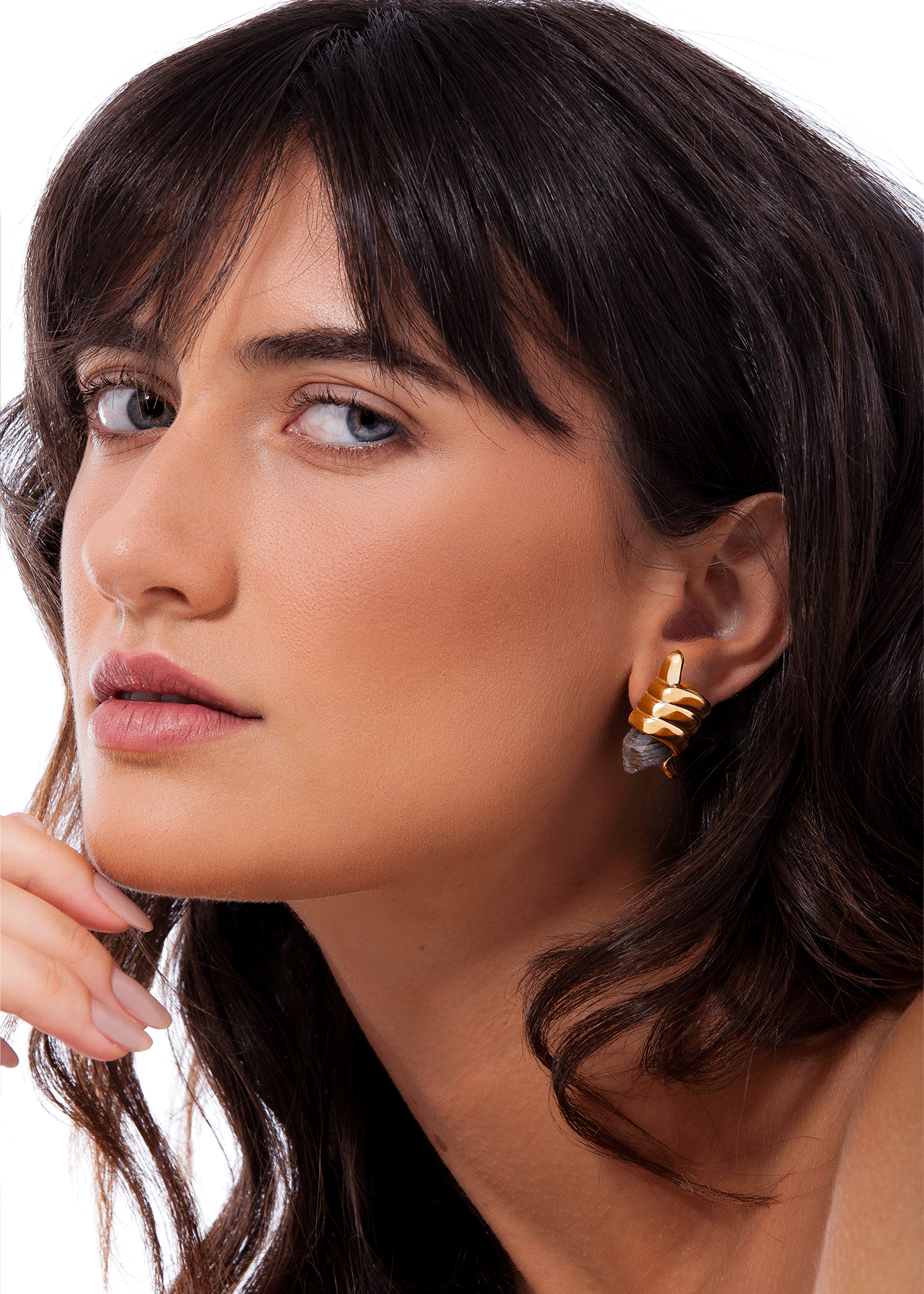 Close-up of a woman wearing gold earrings with a neutral background