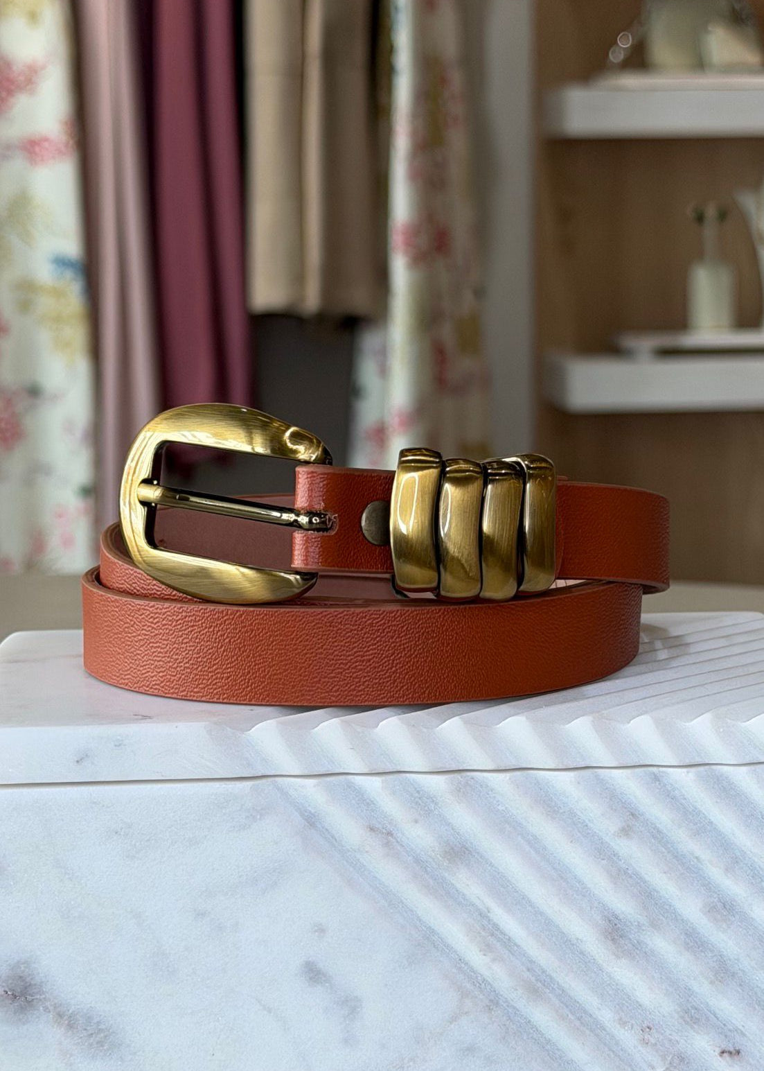 Brown belt with gold buckle on a marble surface