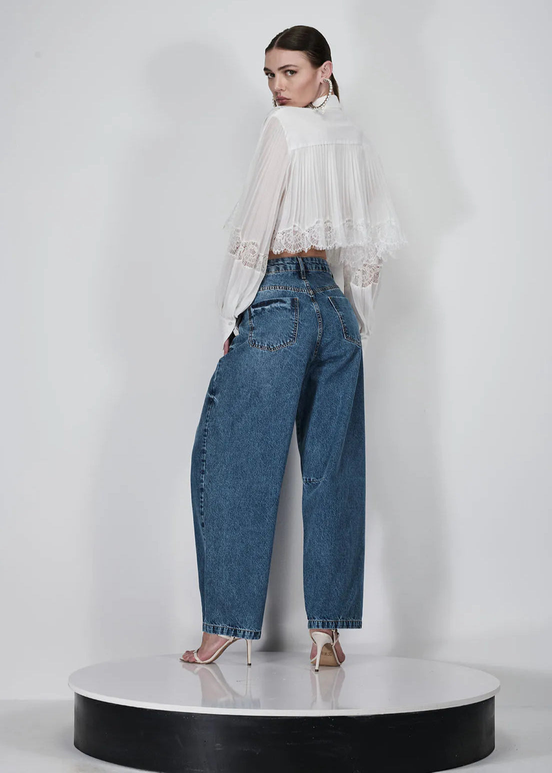 Woman wearing a white blouse and blue jeans on a white background