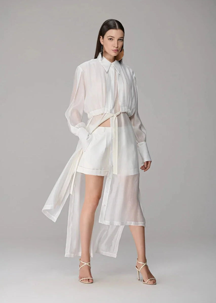 Woman wearing a white outfit with sheer elements on a gray background
