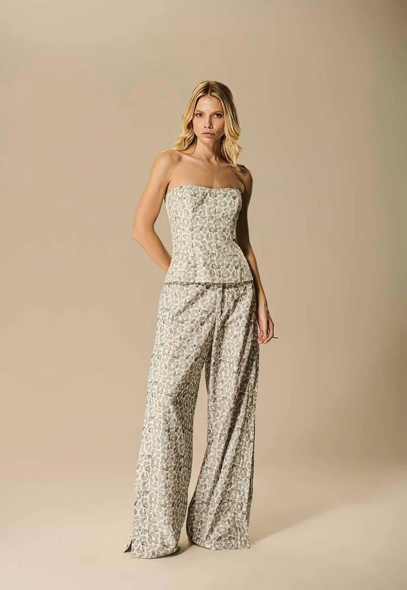 Woman wearing a strapless floral jumpsuit against a beige background