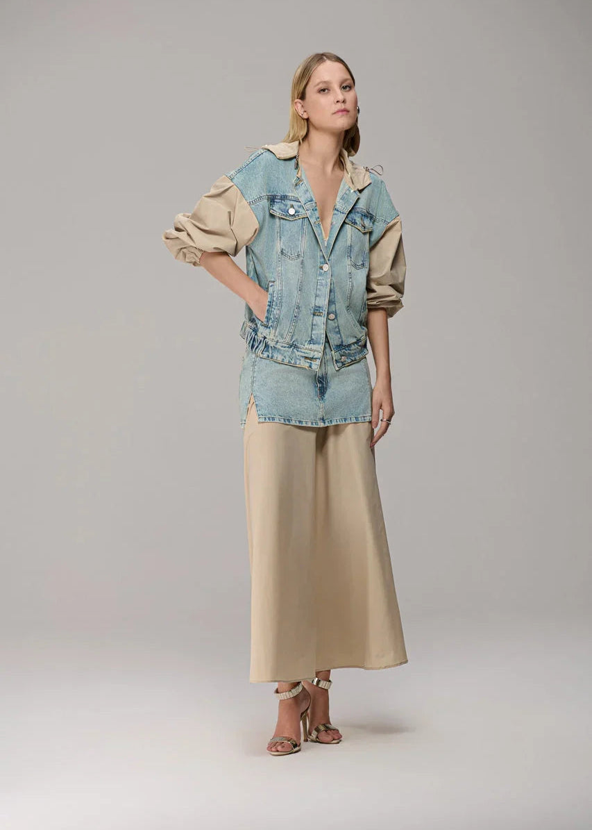 Woman wearing a denim jacket and beige dress on a gray background
