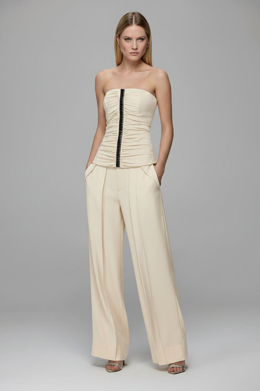 Woman wearing a strapless top and wide-leg pants on a gray background