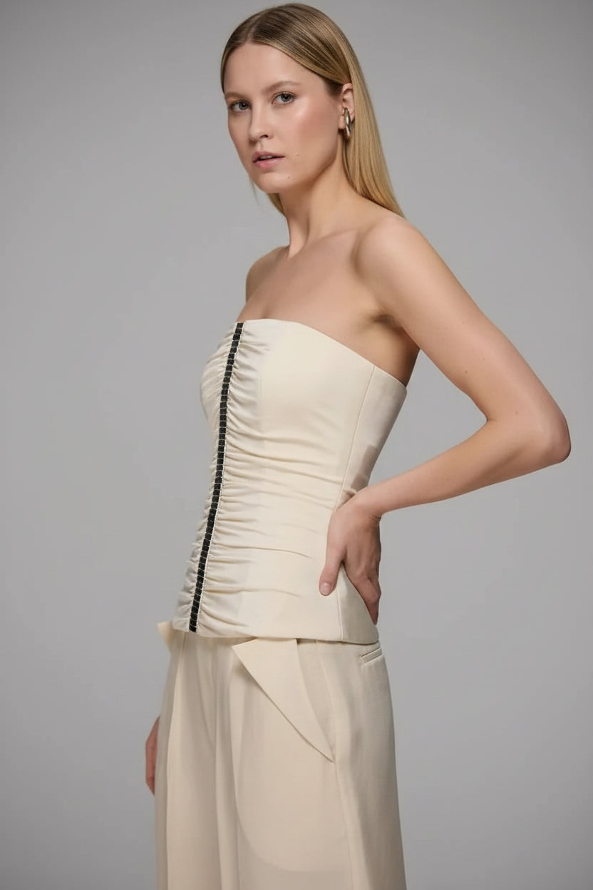 Woman wearing a strapless top and pants with a gray background