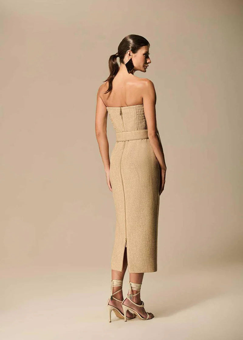 Woman wearing a beige strapless dress with a belt on a beige background