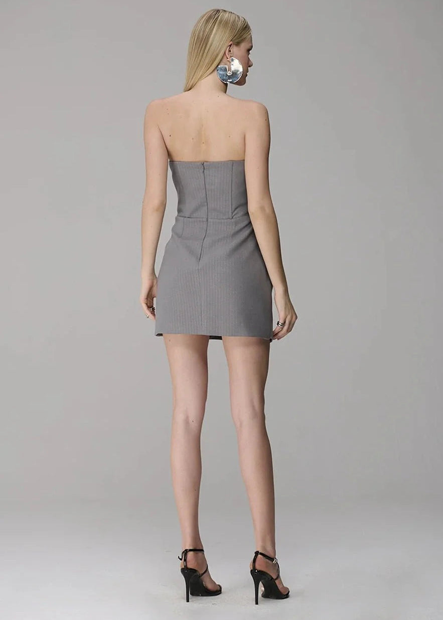 Woman wearing a strapless gray dress on a plain background
