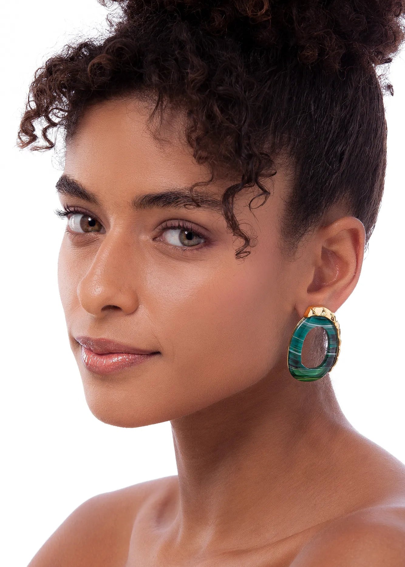 Woman wearing a green earring on a white background