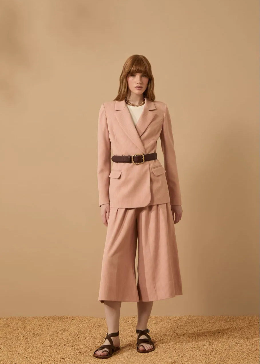 Woman wearing a pink suit against a beige background