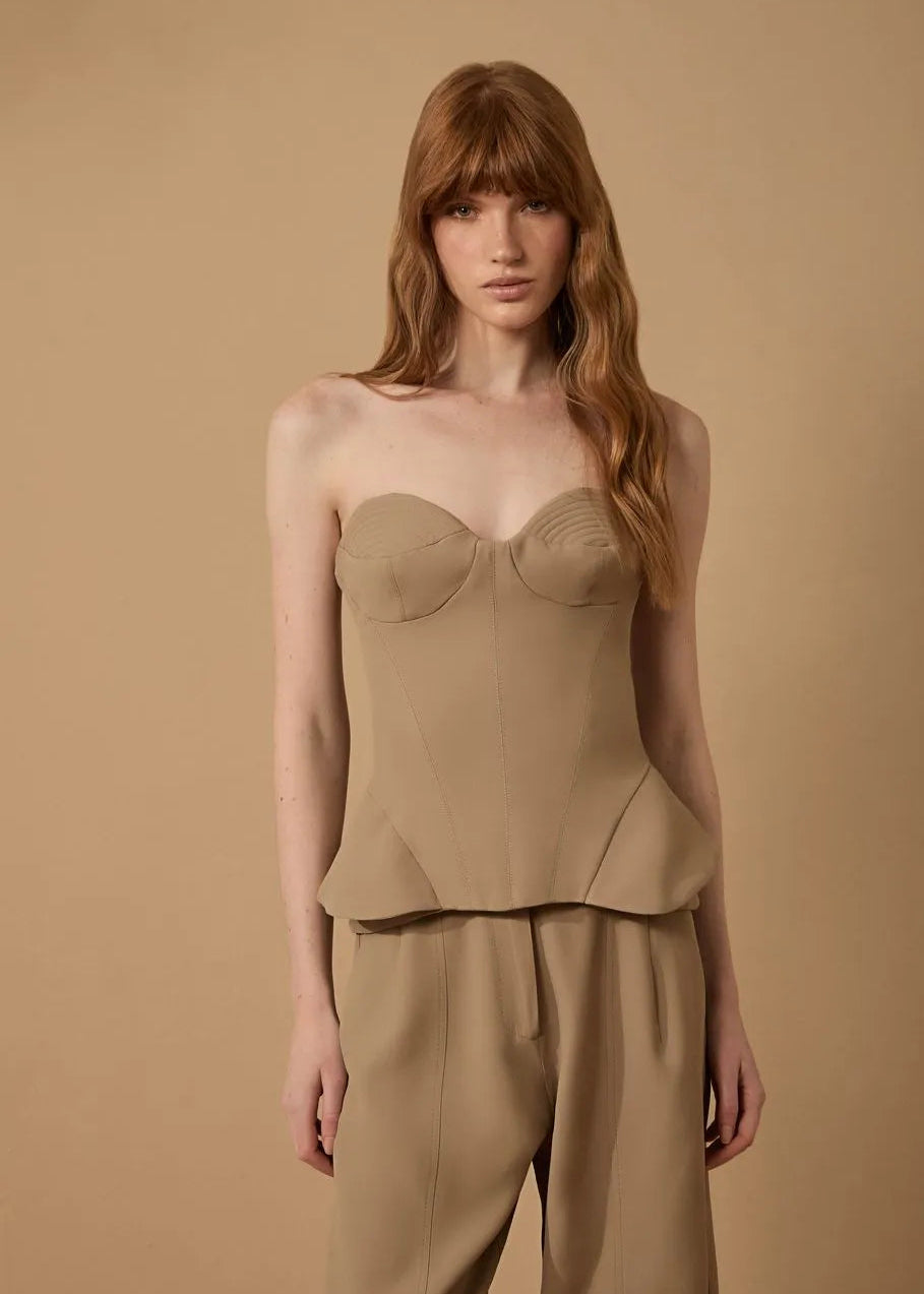 Woman wearing a beige top and pants against a beige background