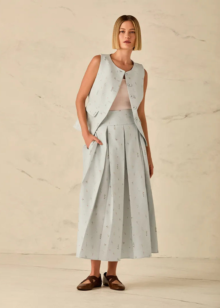 Woman wearing a light gray sleeveless top and skirt set against a beige background