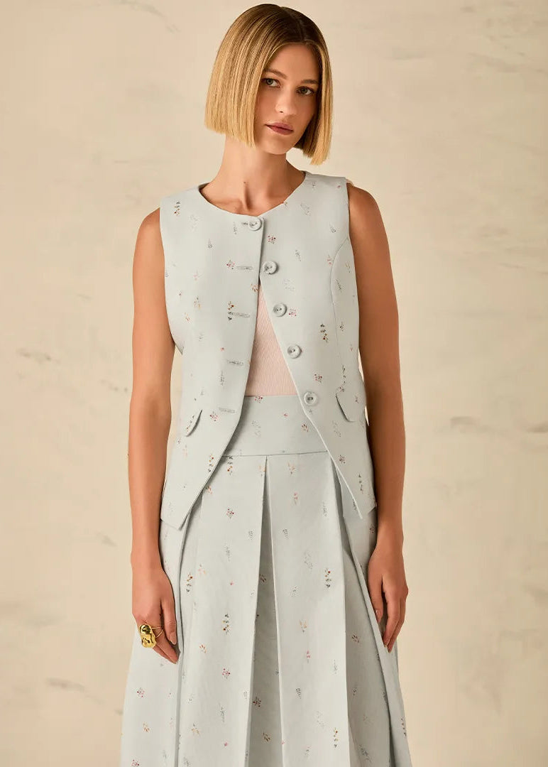 Woman wearing a light gray sleeveless top and skirt set against a beige background