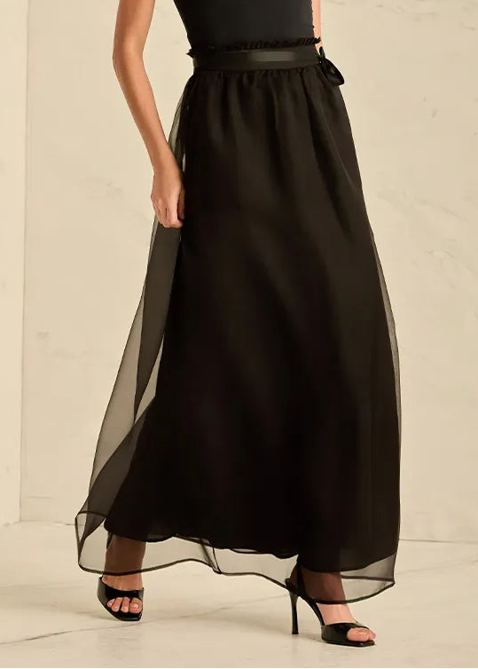 Woman wearing a black sleeveless top and long black skirt