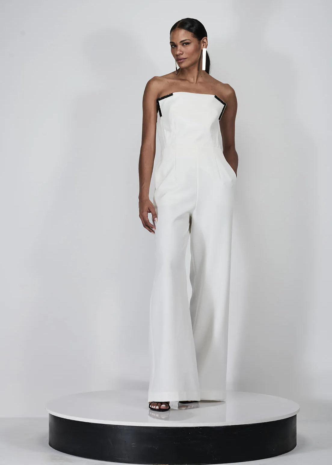 Woman wearing a white strapless jumpsuit on a white background