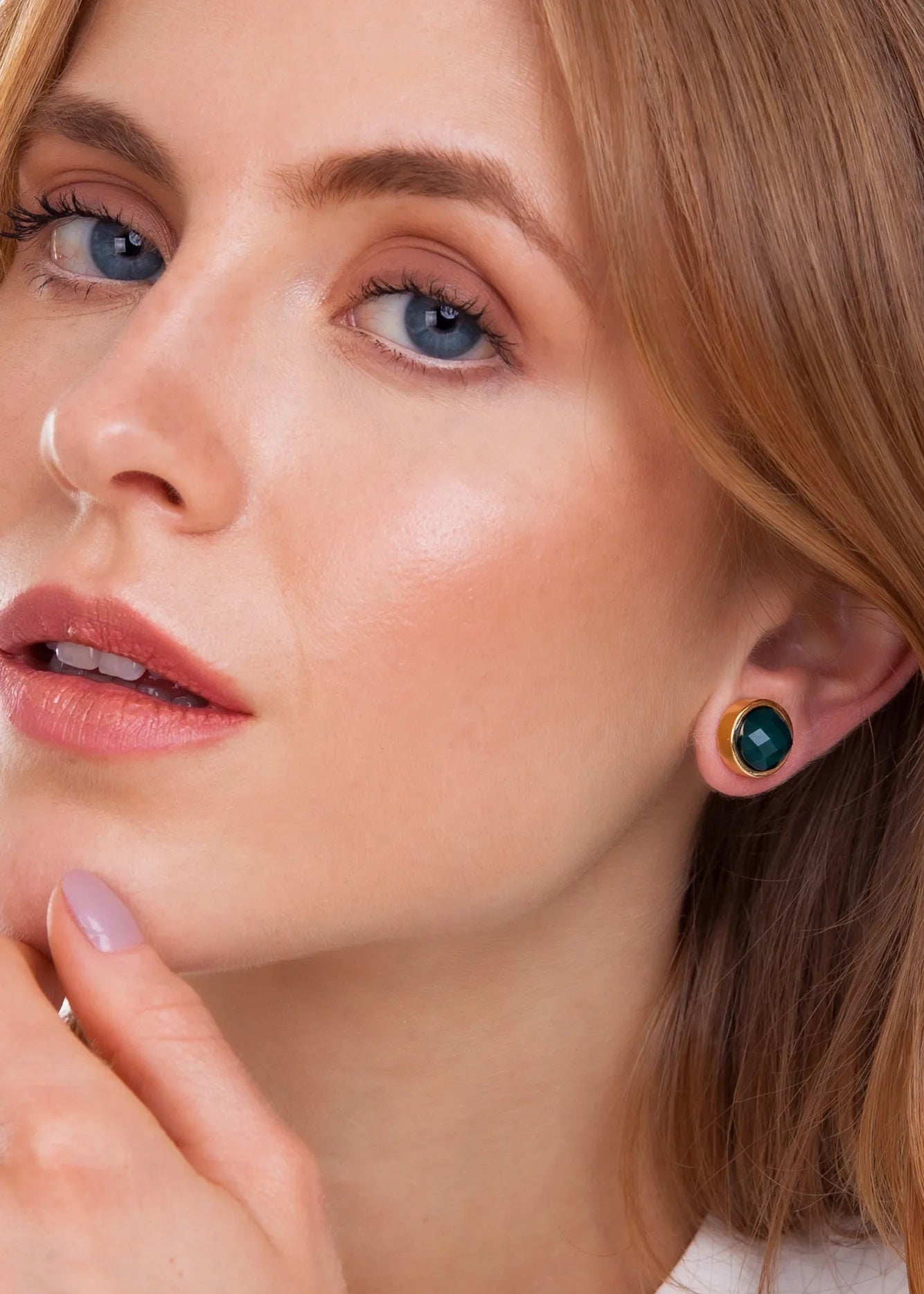 Close-up of a woman wearing a green earring with a gold setting.