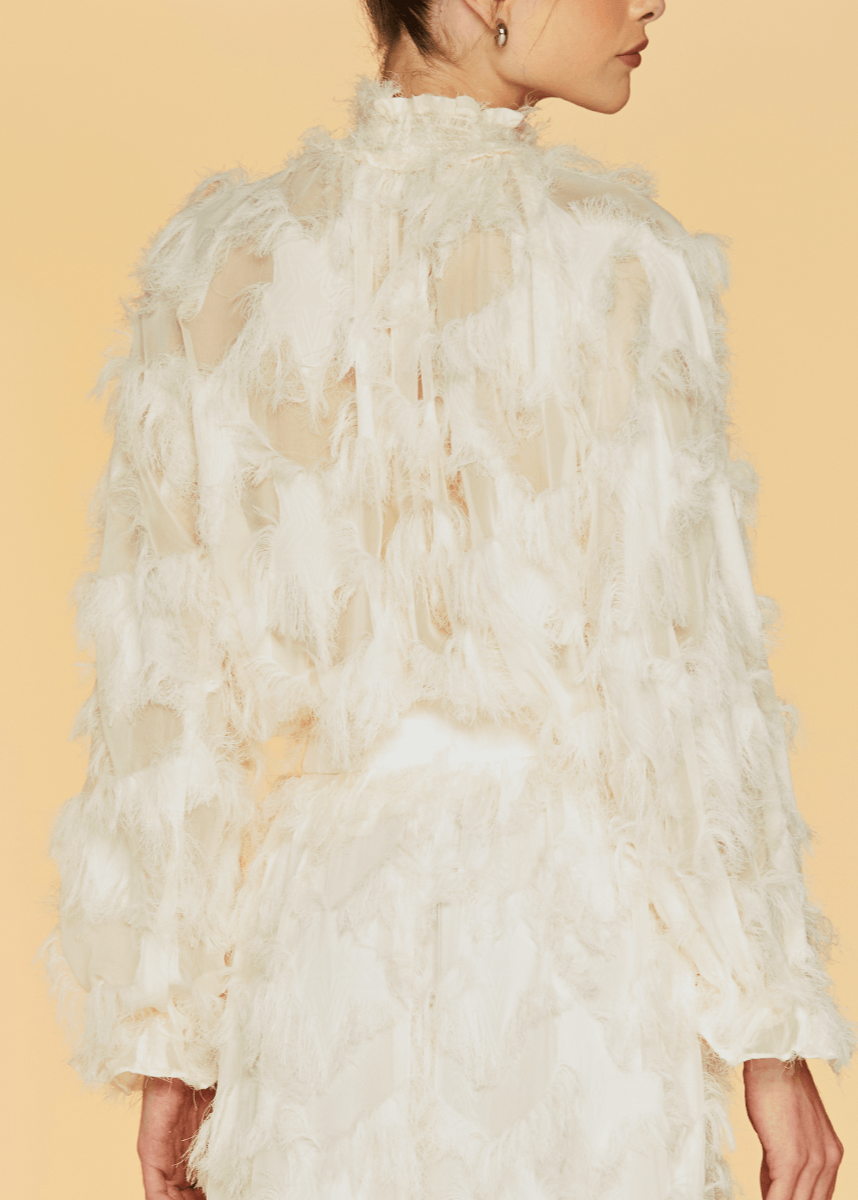 White feathered garment on a model against a beige background