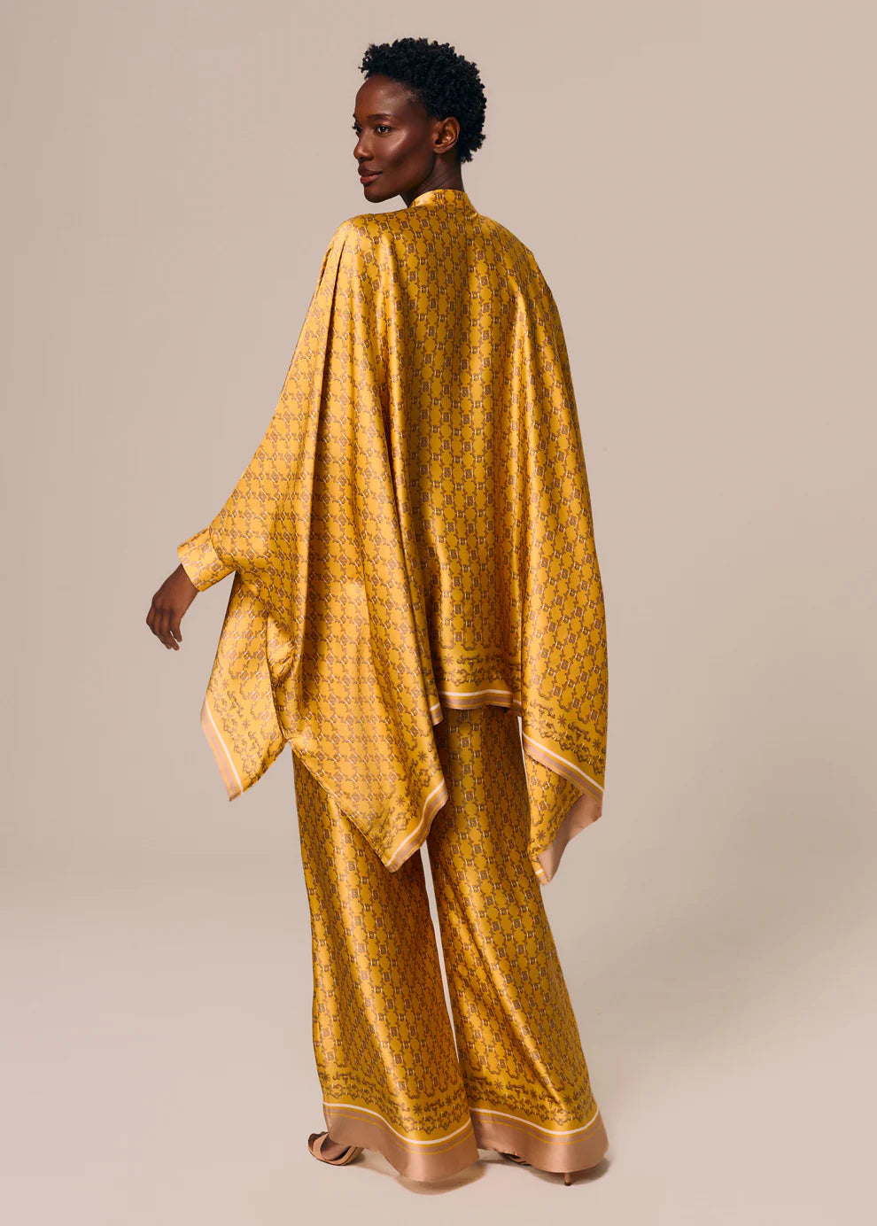 Woman wearing a yellow patterned outfit on a beige background