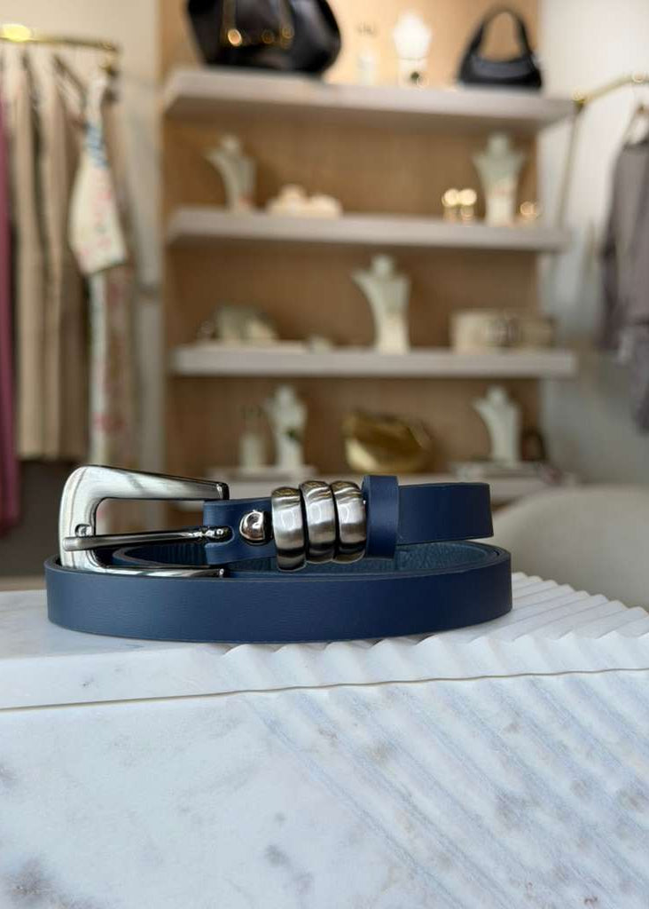 Navy blue belt with silver buckle on a marble surface, blurred store background
