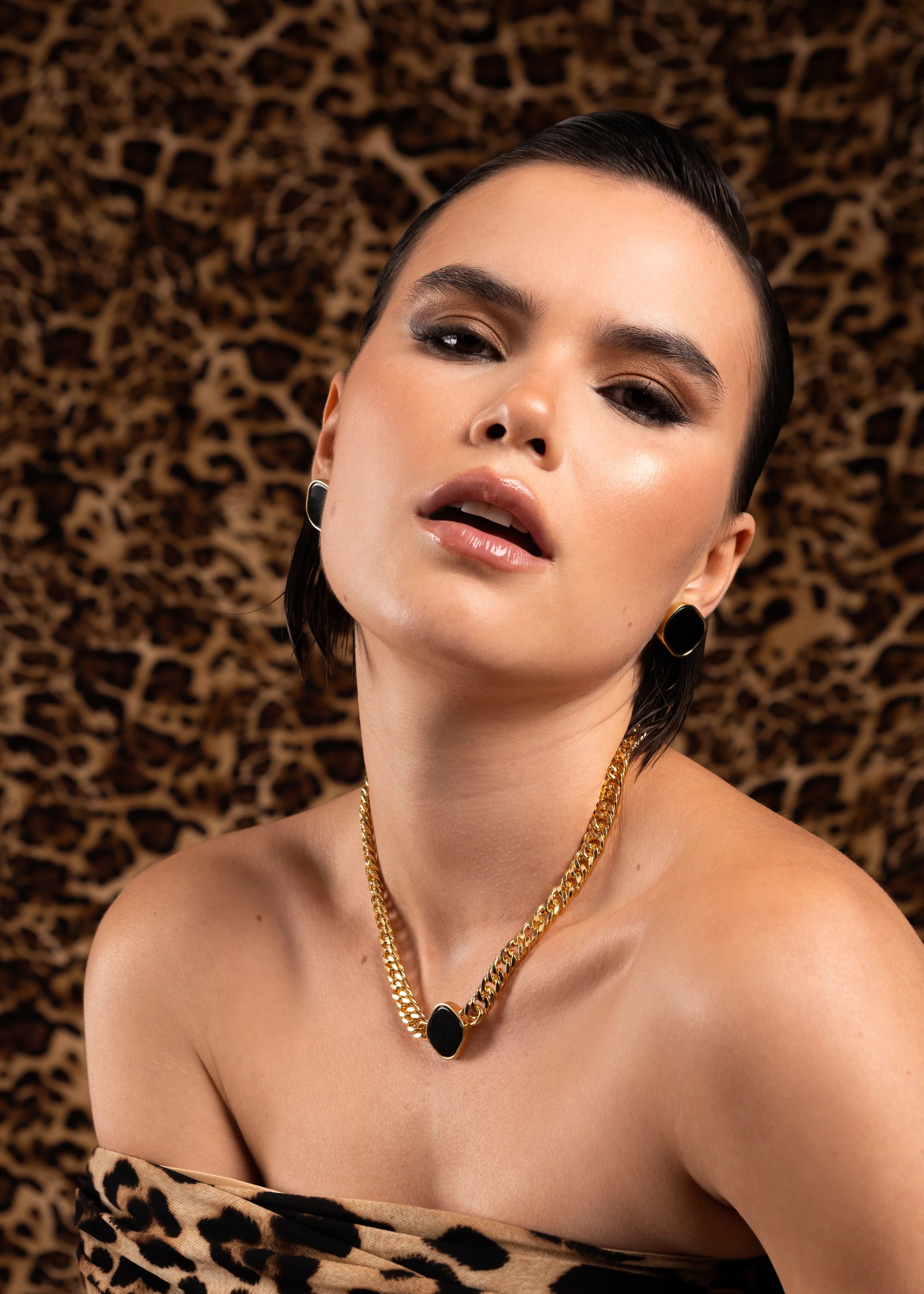 Woman wearing a gold necklace and leopard print top against a leopard print background