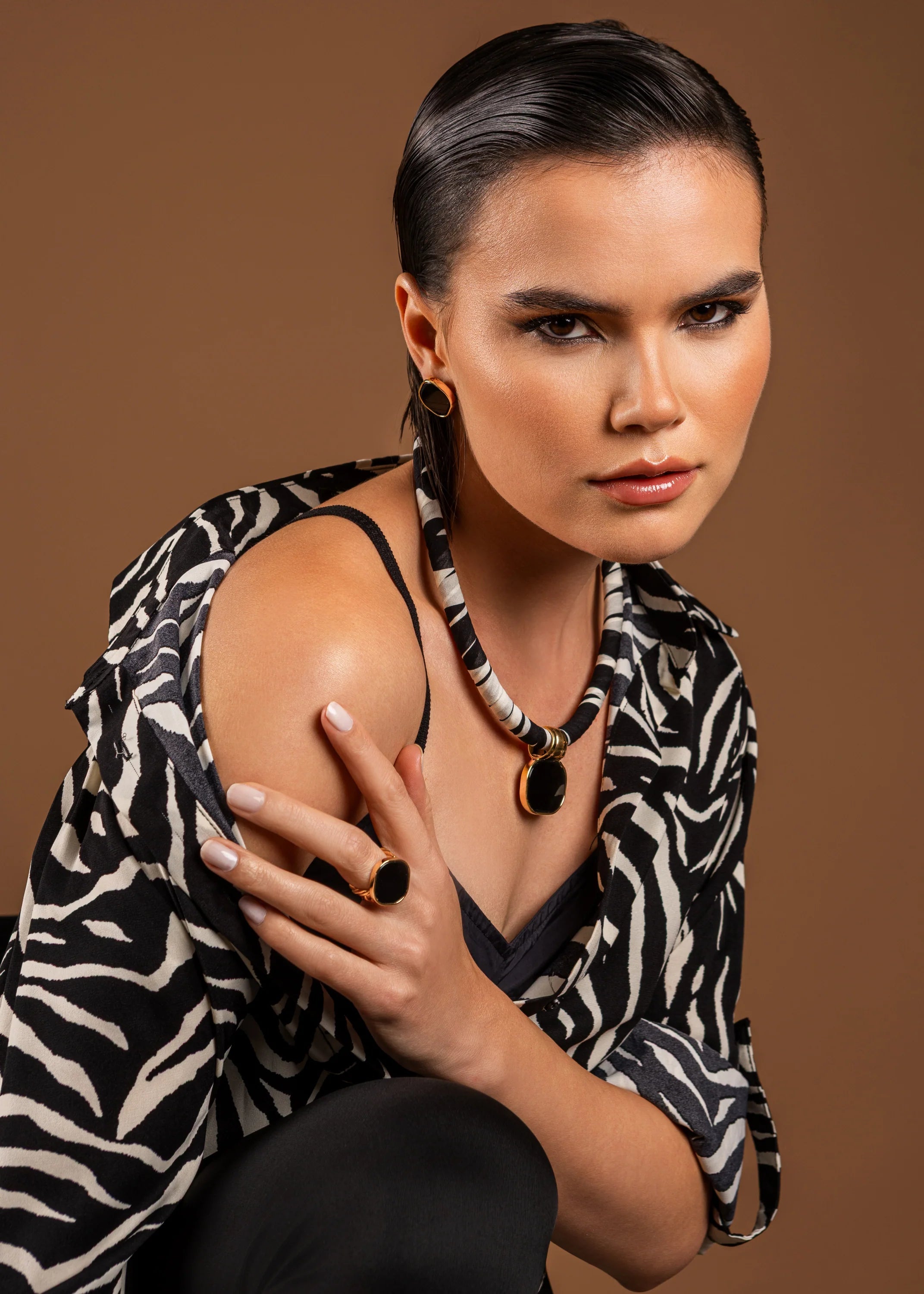 Woman wearing a zebra print jacket and black pants against a brown background
