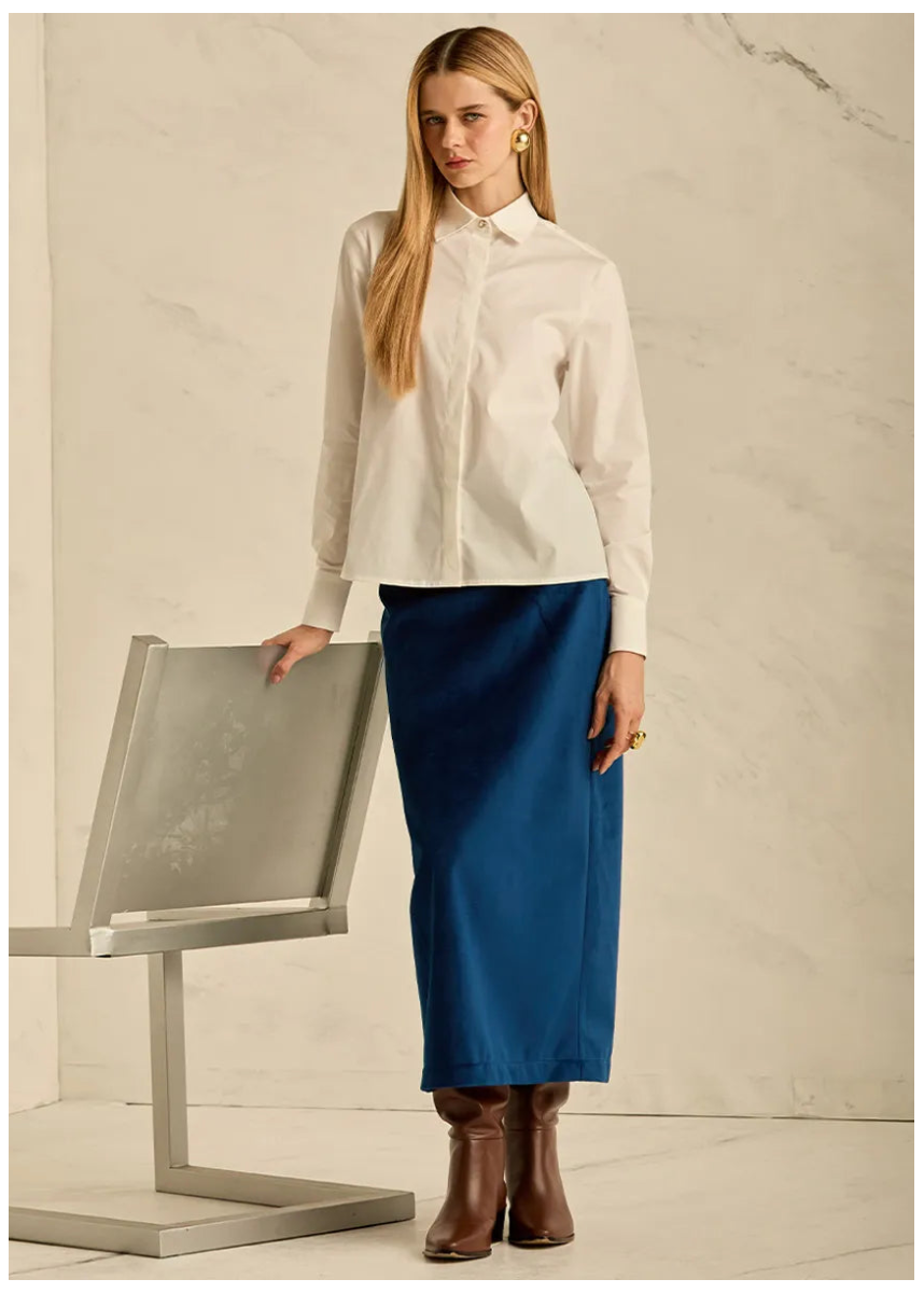 Woman in an off white button down shirt and blue skirt