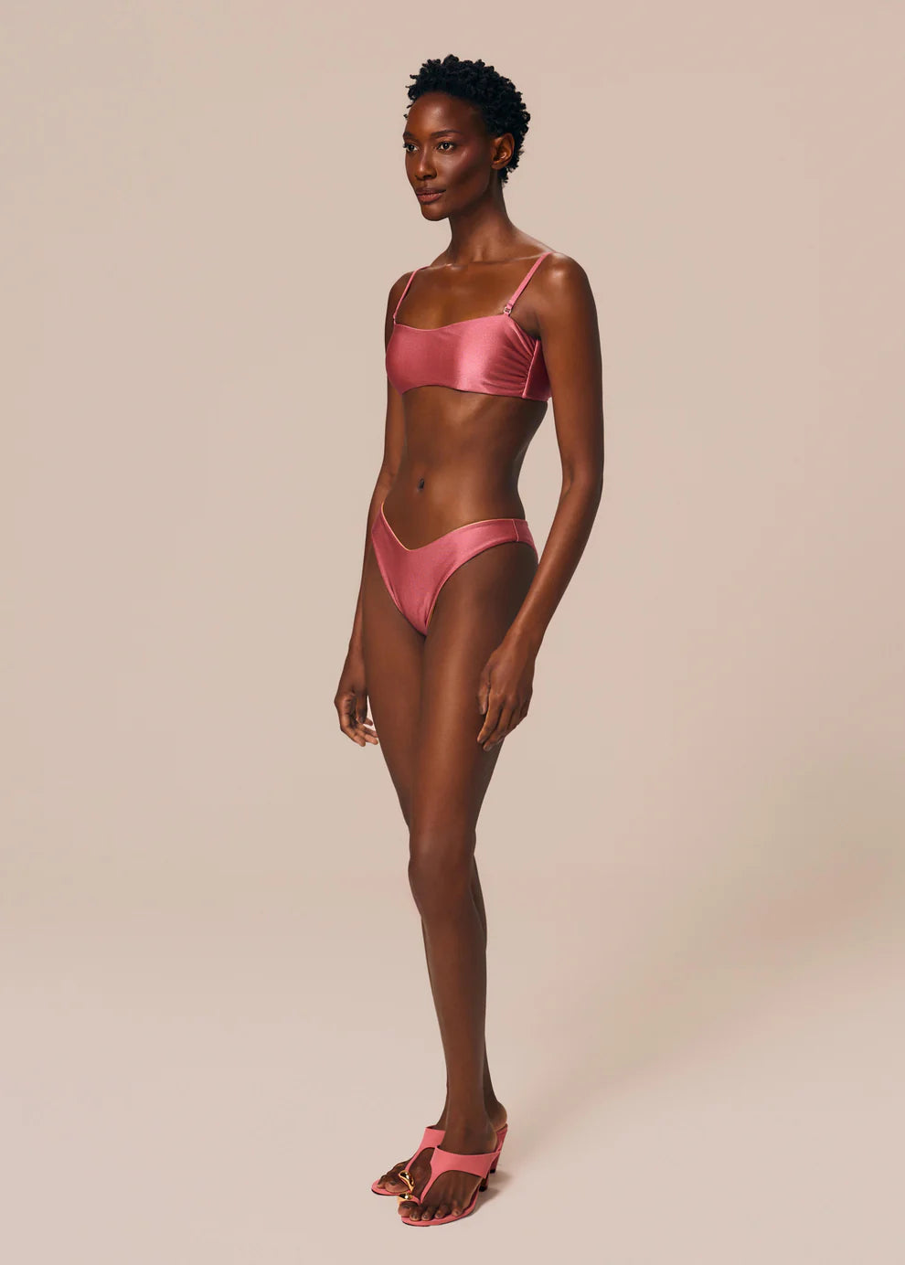 Woman wearing a pink bikini set on a beige background
