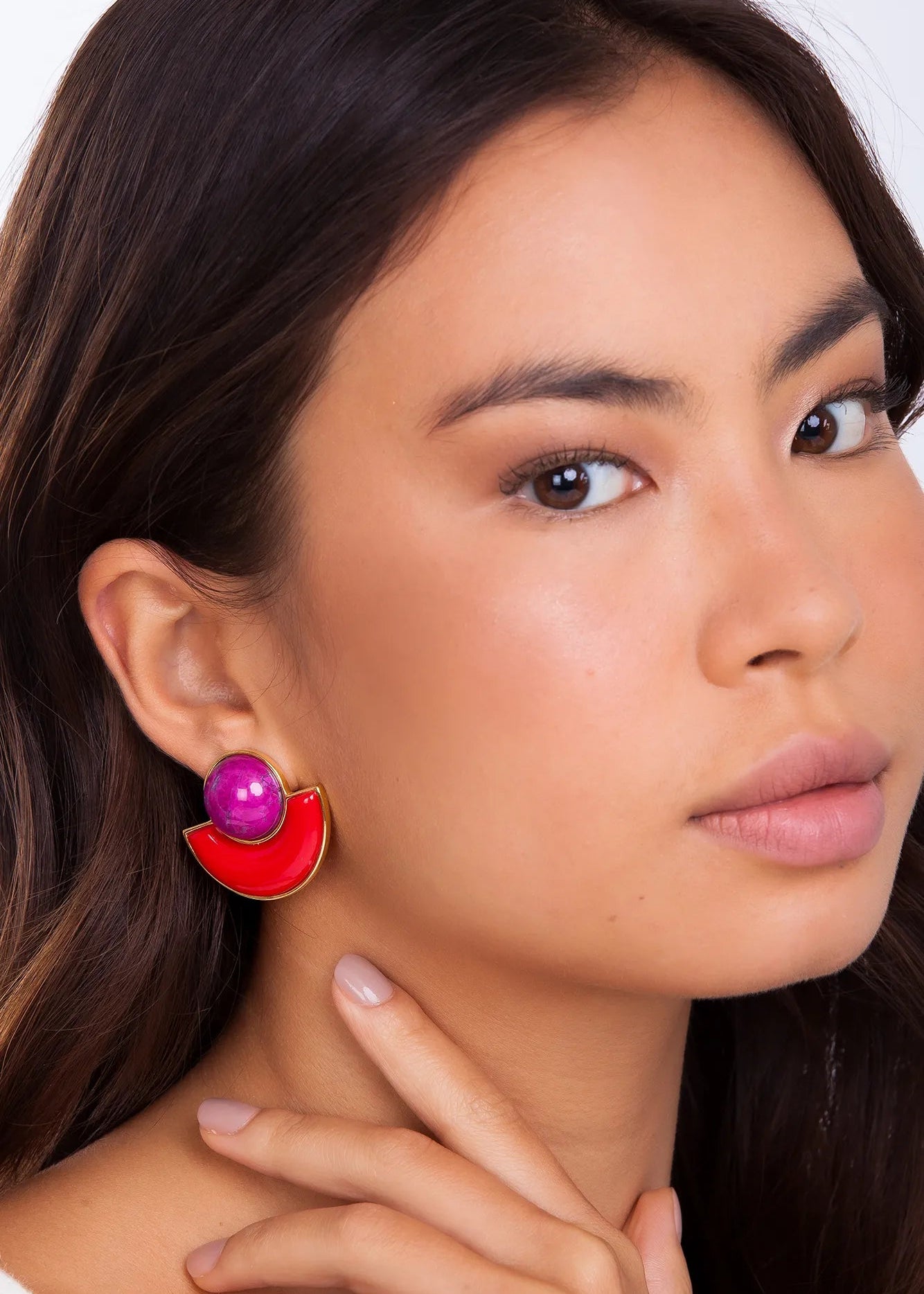 Close-up of a woman wearing a red earring with a purple gemstone.