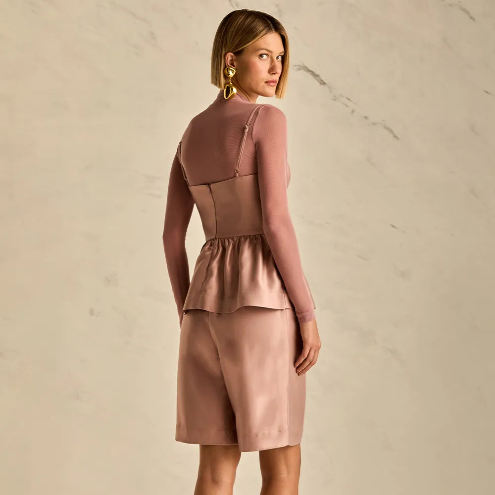 Woman wearing a pink outfit against a beige background