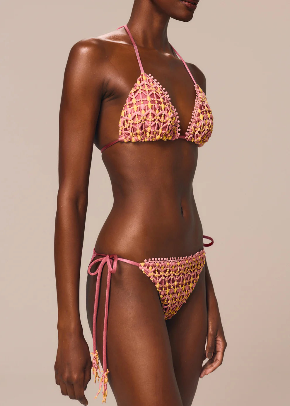 Woman wearing a pink and yellow bikini against a beige background
