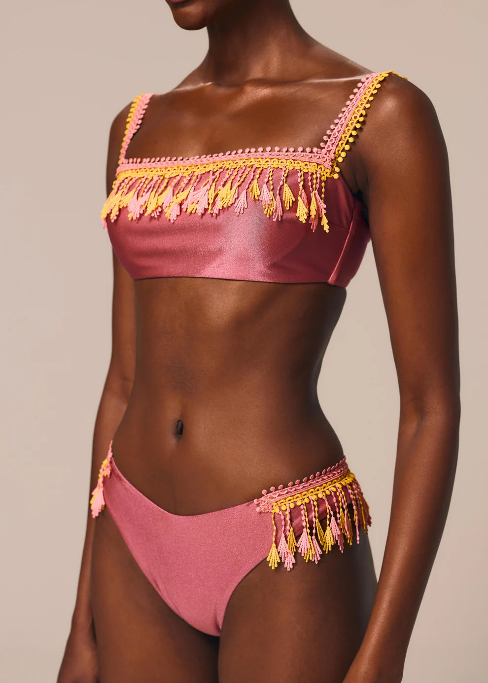 Pink bikini with yellow tassels on a neutral background