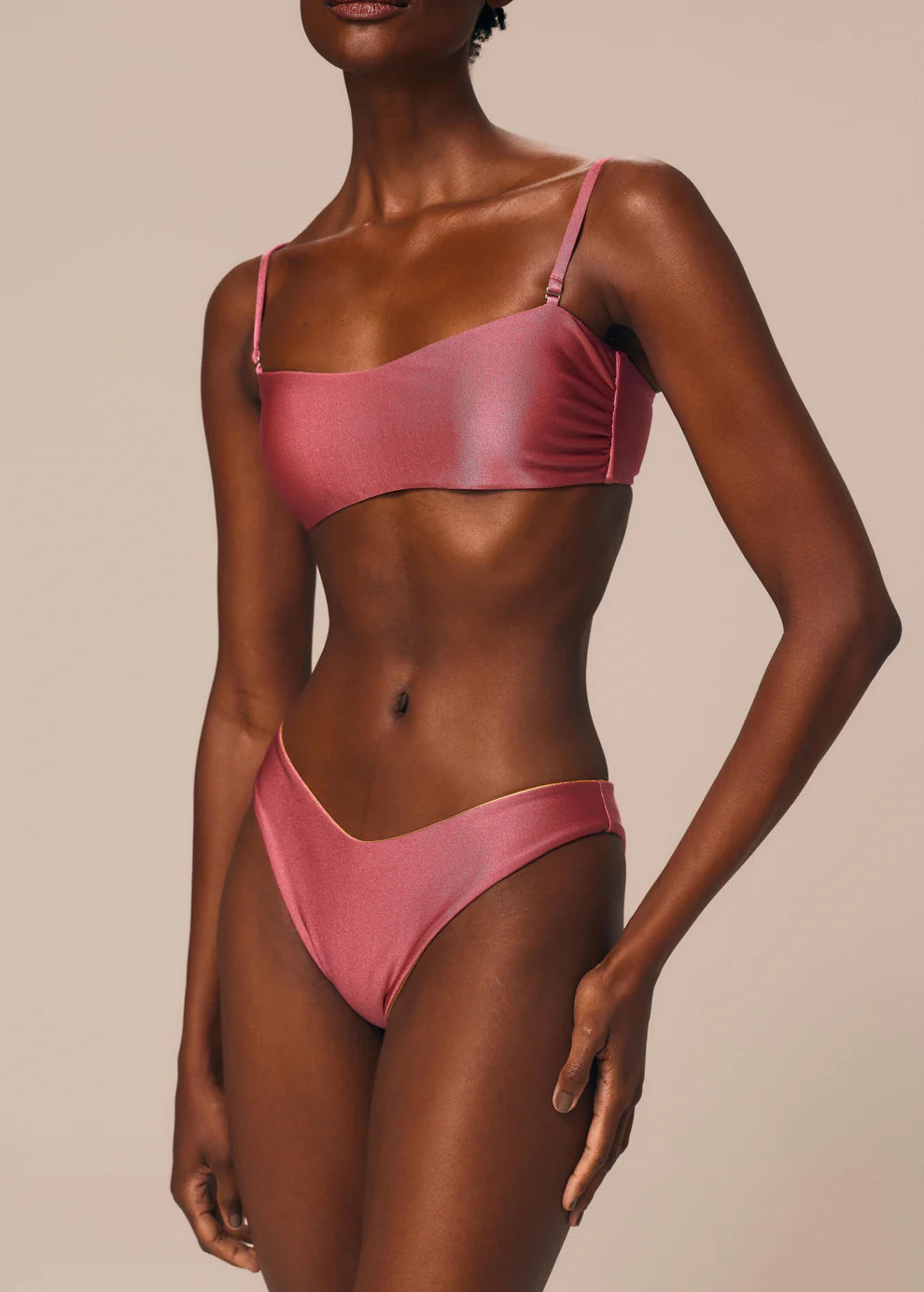 Woman wearing a pink bikini against a beige background