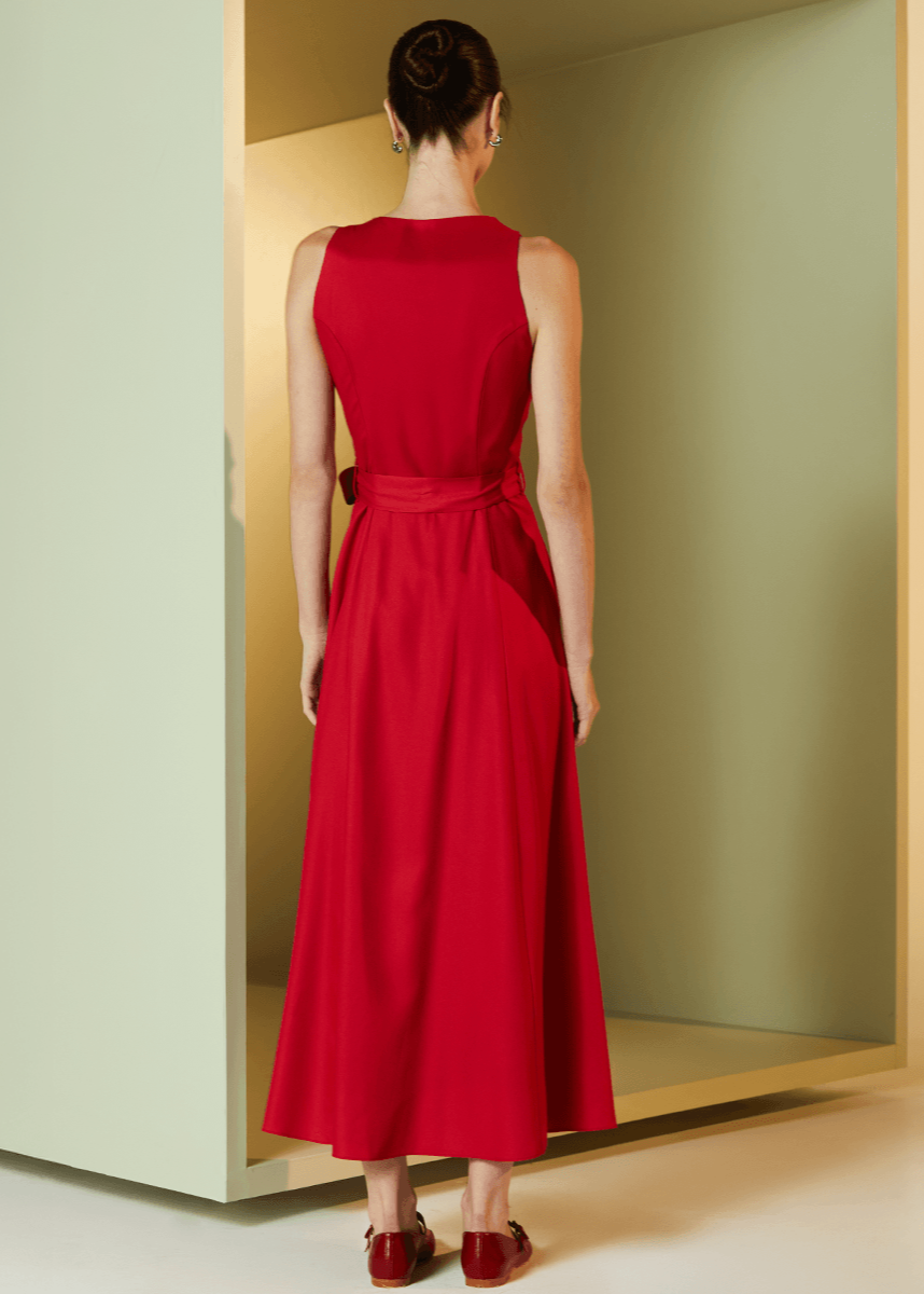 Woman wearing a red dress standing in a minimalistic room with a mirror.