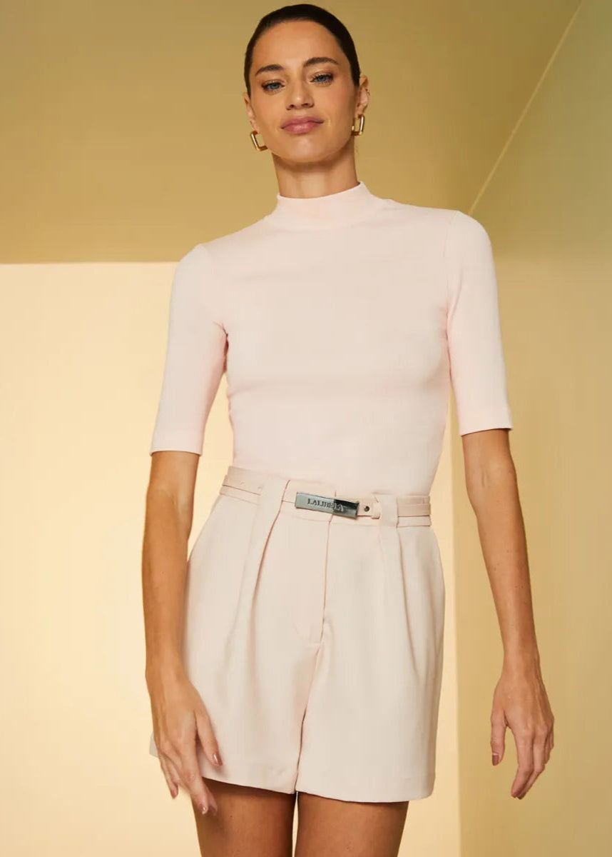 Woman wearing a light pink top and skirt against a yellow background
