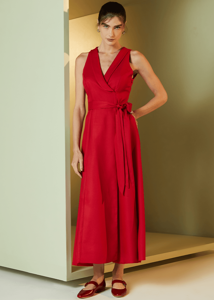 Woman wearing a red dress standing in a minimalistic room with a neutral color scheme.