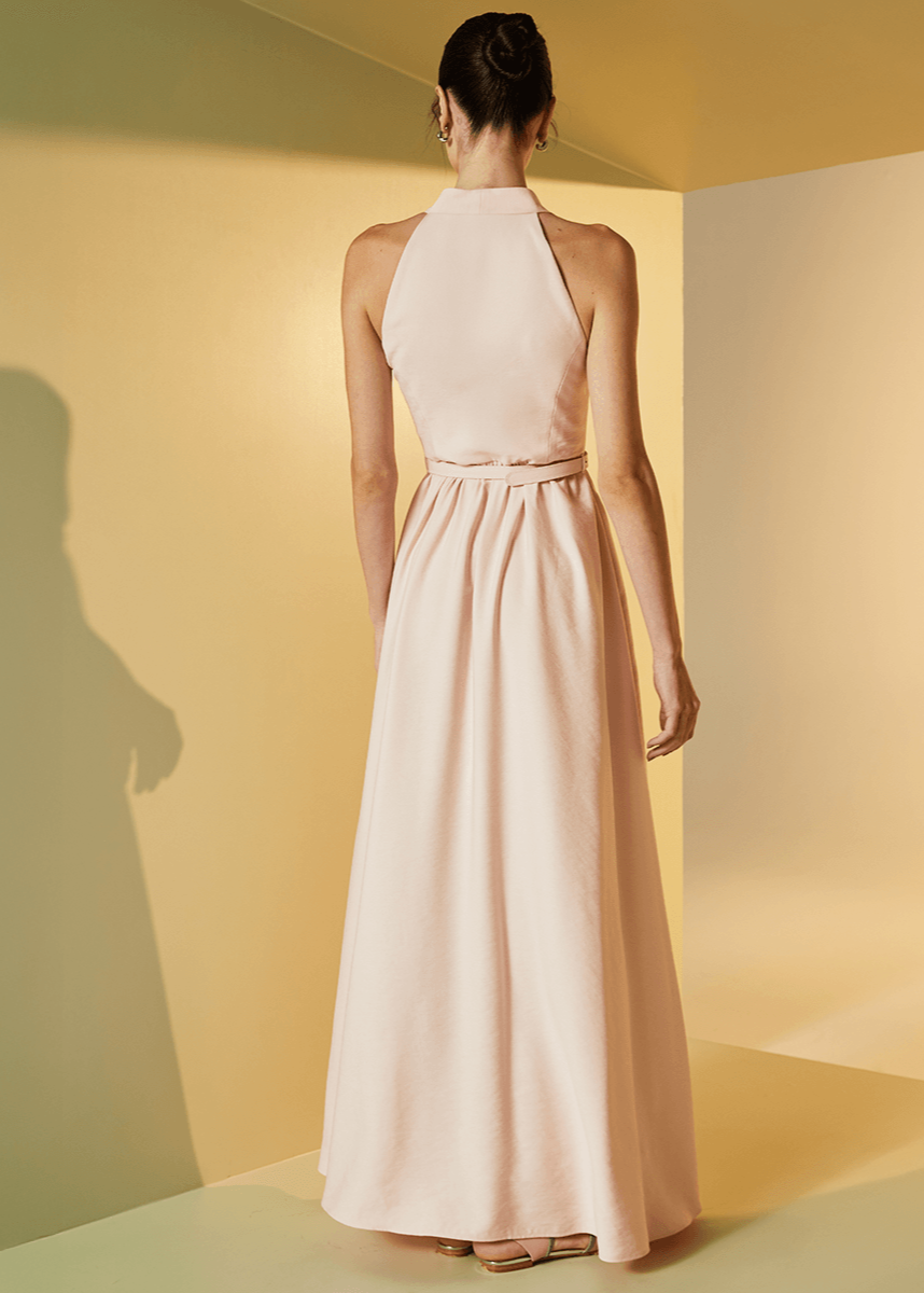 Woman in a long pink dress standing in a room with yellow walls.