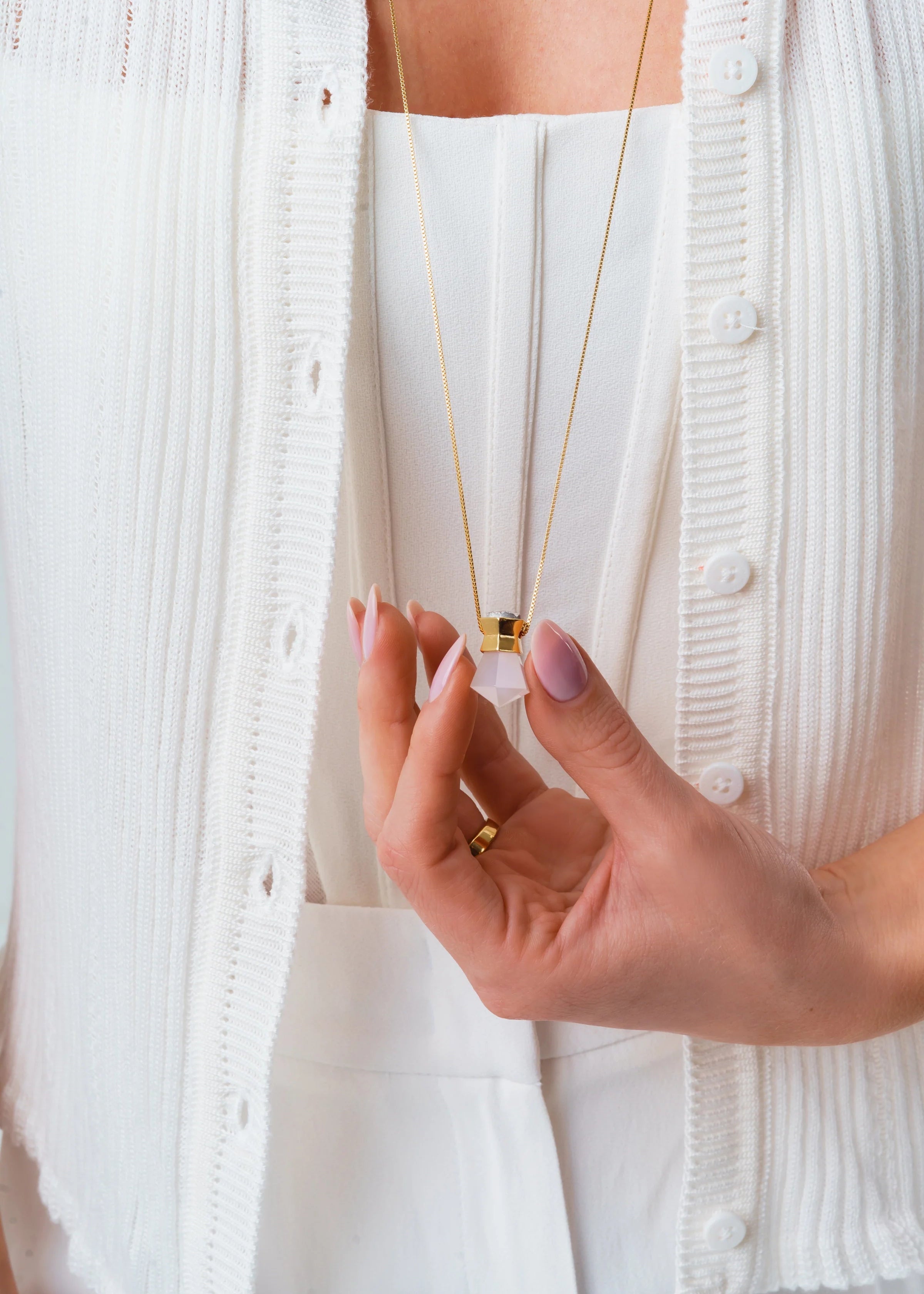 Hand holding a gold necklace against a white background