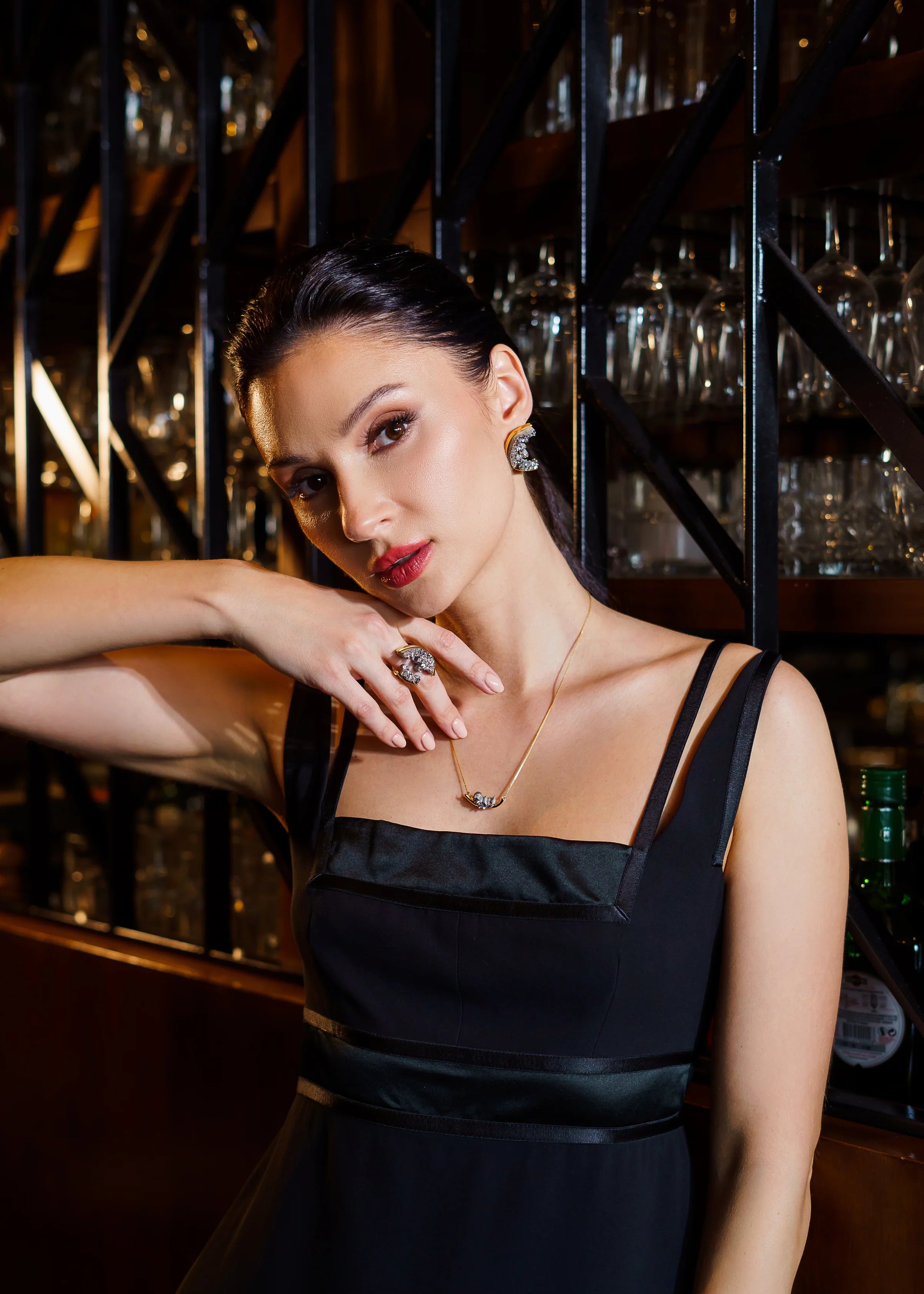 Woman in a black dress with jewelry in a bar setting