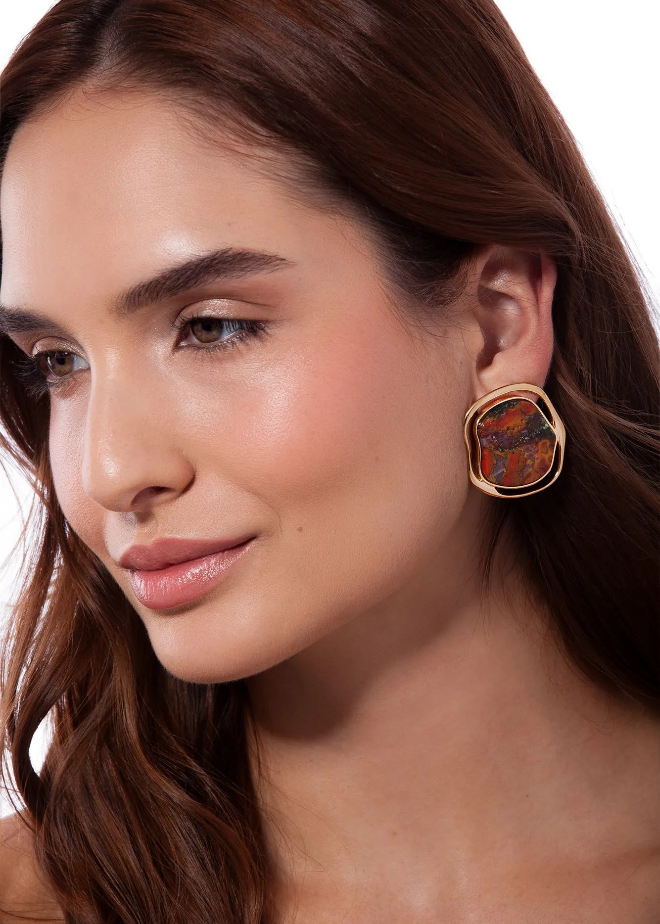 Close-up of a woman wearing a colorful earring on a white background