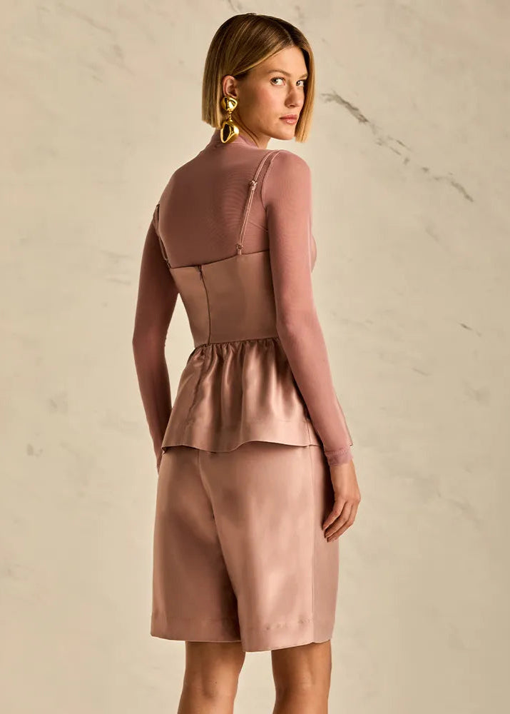 Woman wearing a pink outfit against a beige background