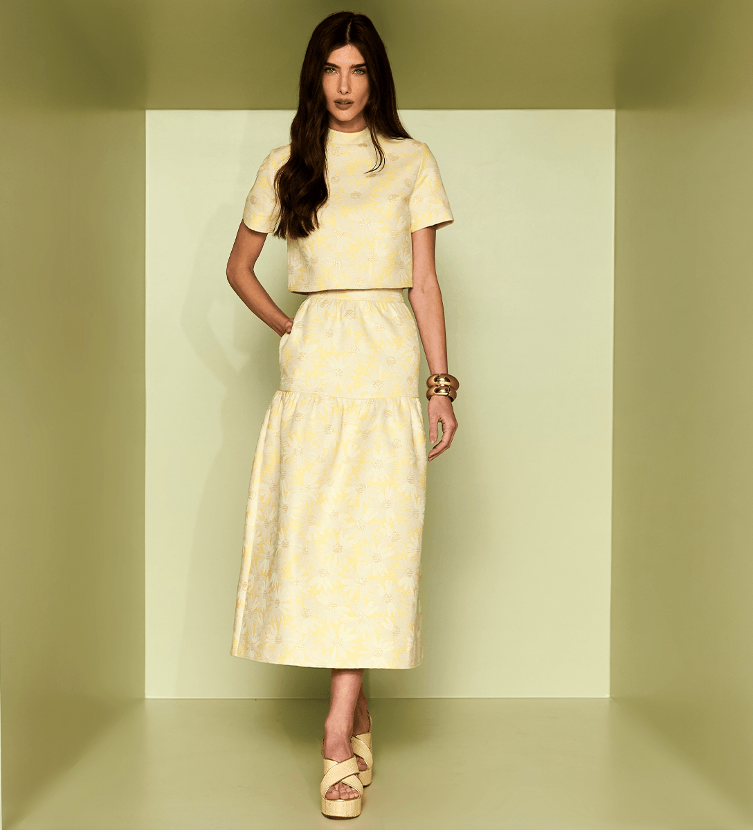 Woman wearing a yellow patterned outfit against a plain background