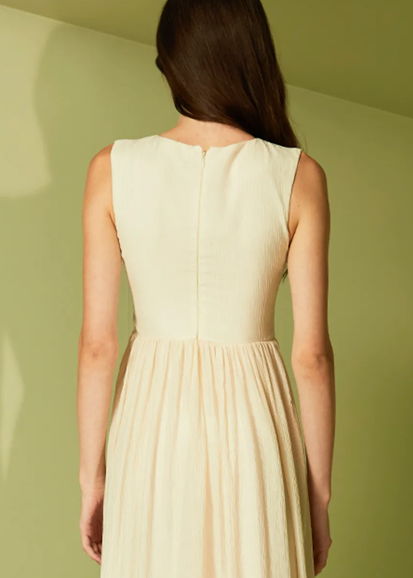 Woman wearing a beige dress against a light green wall