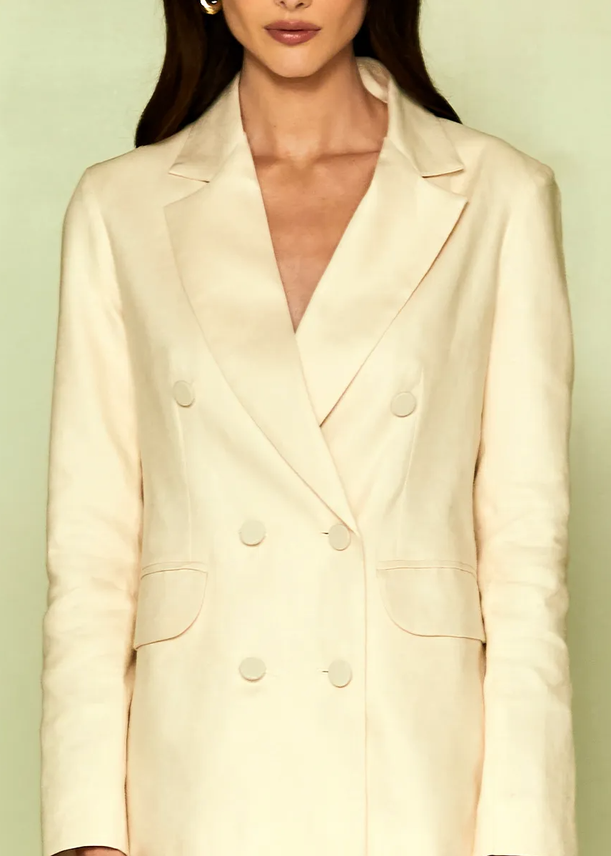 White blazer worn by a person on a light green background