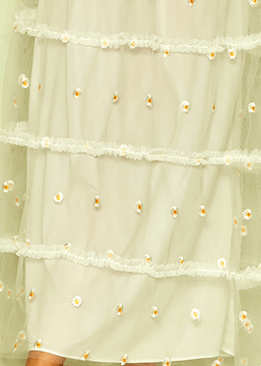 Light green sheer fabric with floral embellishments on a light green background