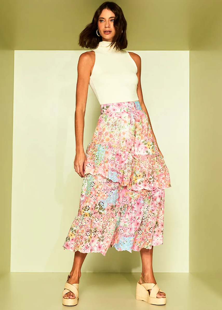 Woman wearing a white sleeveless top and colorful floral skirt on a light green background