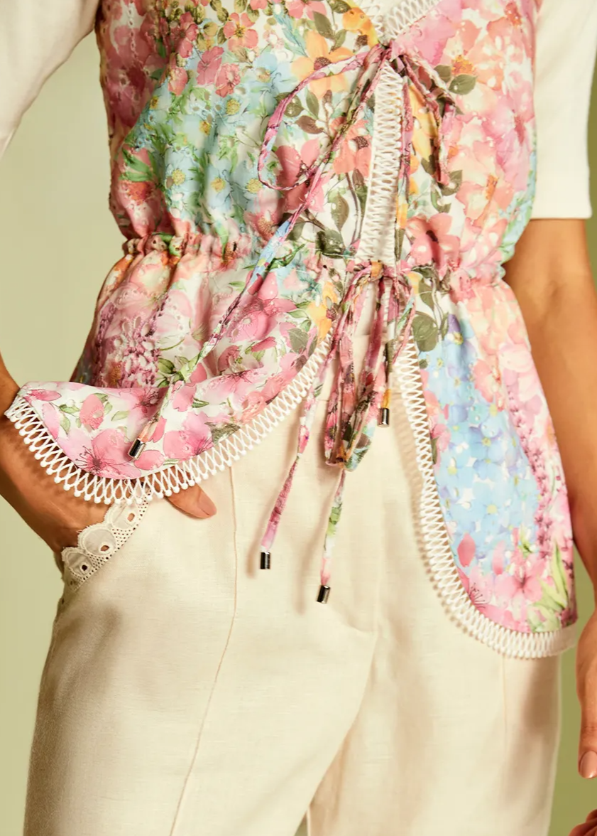 Person wearing a floral apron over a light-colored outfit on a plain background