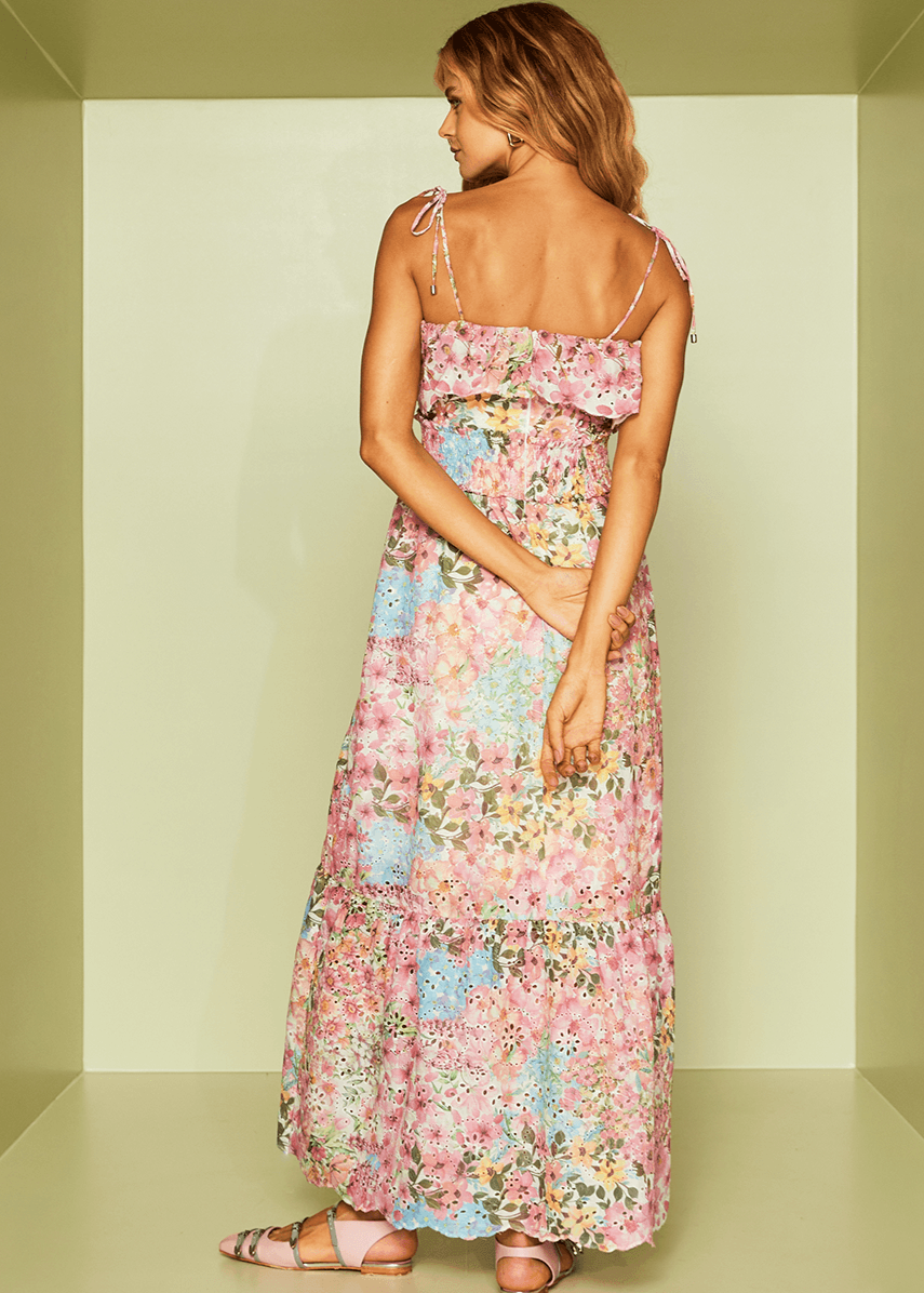 Woman wearing a floral dress standing against a plain background