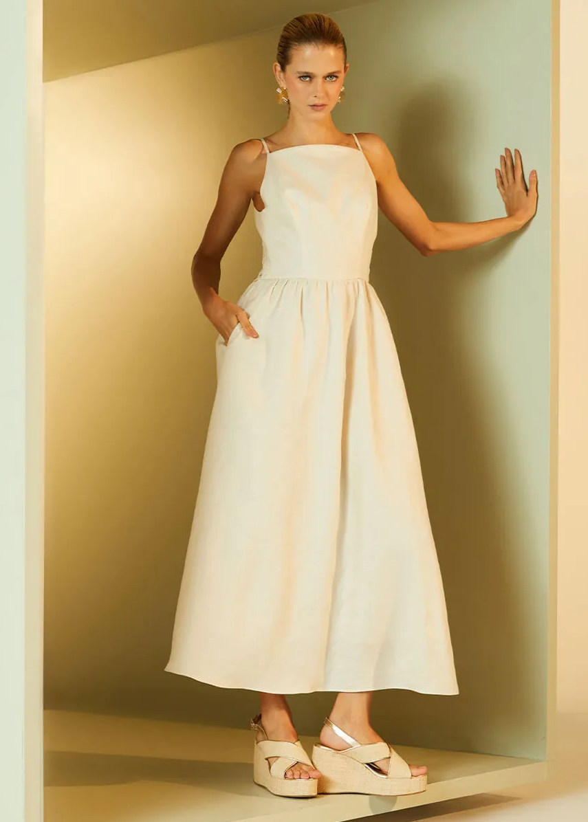 Woman in a white dress standing against a plain wall